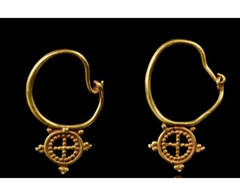 Ca. 600 AD  A matched pair of gold earrings, each comprising a circular hoop with a hook and clasp closure. Below each hoop, 