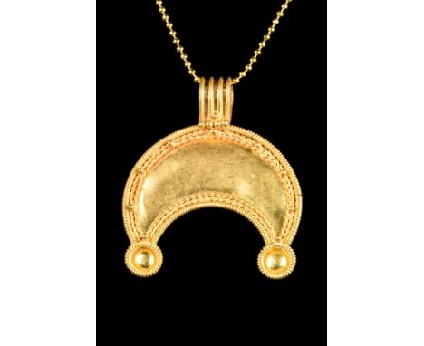 Ca. 100 AD A gold lunar amulet comprises a crescent moon with a suspension loop, corded border, and applied spheres. In Roman