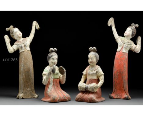 Ca. 618-907 AD  A delicate figure of a female dancer wearing a long brown gown with a white shrug. Her hands are covered in s