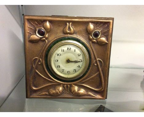 An arts and crafts mantle clock with copper front in art nouveau design.