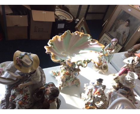 Four ceramic figurines, a ceramic candlestick with decorative figurines and gilding and a ceramic plate on stand with intrica