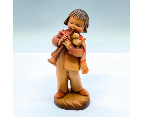 A vintage carved figure of a boy playing a clarinet with a bird singing on his arm. Artist carved name on the side. Anri embo