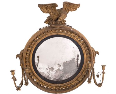 A Regency carved giltwood and gesso circular convex girandole mirror:, surmounted by a figure of an eagle with outspread wing