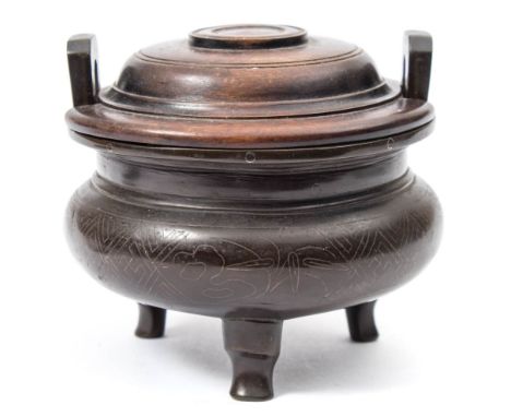 A small Chinese silver inlaid bronze tripod censer and wood cover: with flattened angular loop handles, inlaid with circular 
