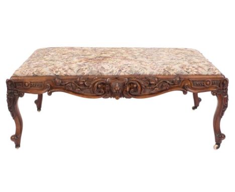 A Victorian carved walnut rectangular stool of large size:, with an upholstered machine tapestry slip in seat, the shaped apr