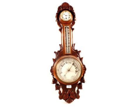 An aneroid barometer with clock in leaf carved oak case (cracked glass)