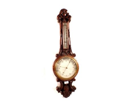 An aneroid barometer in heavily carved oak case (cracked glass)