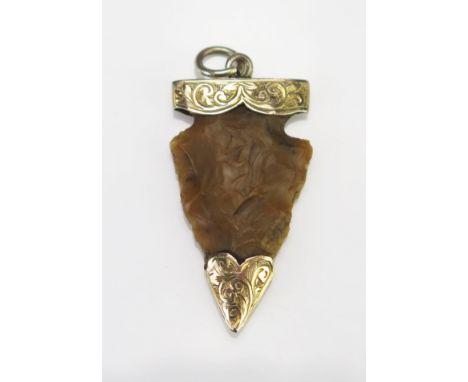 A Stone Age and later Flint Arrow Head Pendant in a precious yellow metal mount with chased scroll decoration, KEE tests as 9
