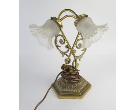 A brass twin branch table lamp, with scrolling branches, on a hexagonal weighted base, with opaque glass shades, 38cm high 
