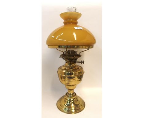 A brass oil lamp with mustard glass shade Condition Report: Available upon request