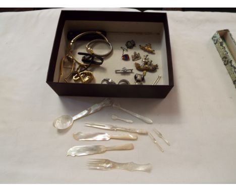 A mixed selection to include military cap badges, watches and mother of pearl of spoons, knives etc