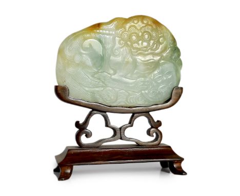 A Chinese three colour jade 'Buddhist lion' belt buckle, 19th century, carved in low relief with the recumbent lion grasping 