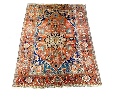 An antique Heriz brick red ground carpet, with large central floral medallion within a wide conforming border, 370cm x 290cm*