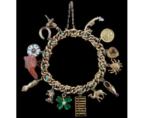 An Edwardian 15ct gold, seed pearl and turquoise set curb link charm bracelet, the links with shamrock motifs and hung with f