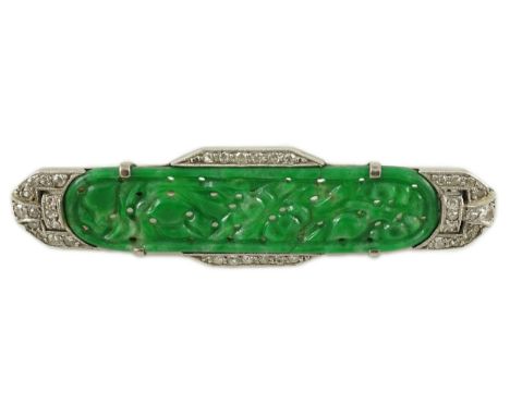 An Art Deco white gold, jadeite and diamond set bar brooch, the jadeite with carved foliate decoration, the sides and pierced