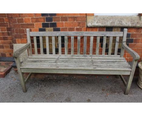 A WELL-WEATHERED TEAK SLAT BUILT THREE PERSON GARDEN BENCH 