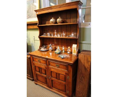 A STAINED OAK FINISHED DRESSER with twin shelf plate rack back, the base unit having two inline drawers, over two panelled cu