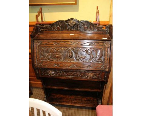 A LATE 19TH CENTURY CARVED OAK FRONTED STUDENT'S DESK with open book shelf base 