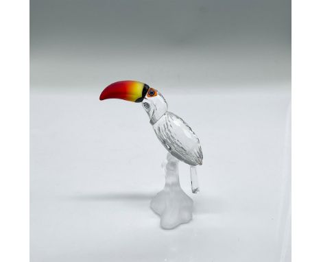 Clear faceted crystal figure of a toucan with bright red/orange/yellow frosted beak, perched on a frosted crystal base. Part 