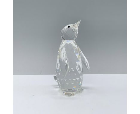 A clear penguin stands proudly with its wings slightly opened and its head tilted upwards in wonder. Swarovski backstamp. Thi