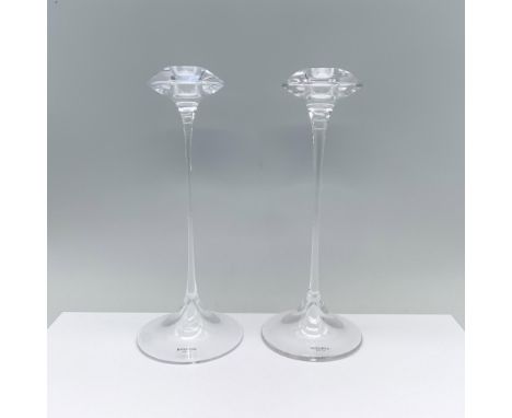 An elegant pair of clear candlesticks featuring a rounded base, a slender stem, and a cymbal-shaped top with a candle holder.