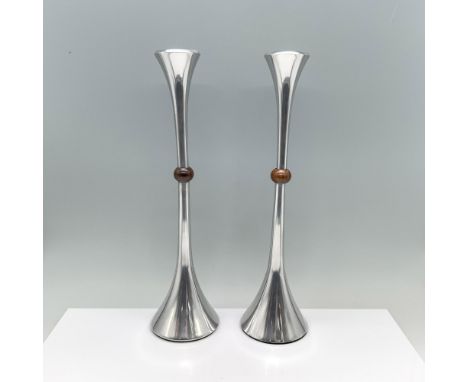 A pair of silver-colored candlesticks, boasting a trumpet-like top, a slender body, and a flat round base with a stylish wood