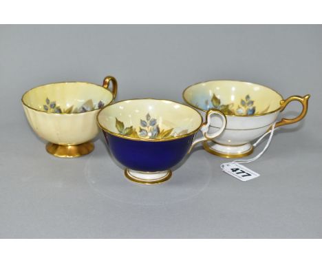 THREE AYNSLEY CABBAGE ROSE TEA CUPS DECORATED BY J.A. BAILEY, comprising pattern no. 1028 with solid gilt handle and foot, cu