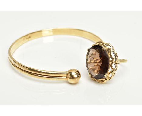 A 9CT GOLD TORQUE BANGLE AND 9CT GOLD SMOKEY QUARTZ DRESS RING, a yellow gold hollow cuff bangle with ball pattern terminals,