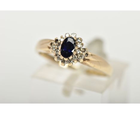 A 9CT GOLD CLUSTER RING, a blue oval stone believed to be sapphire, set with a surround of round brilliant cut diamonds, lead