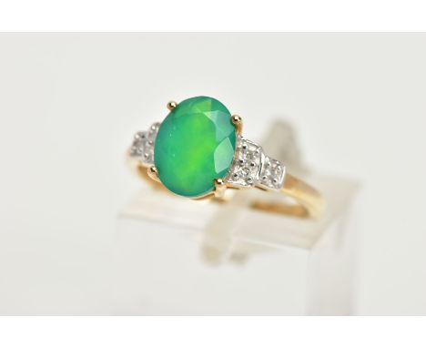 A 9CT GOLD GEM SET RING, designed with a four claw set oval cut green stone, flanked with stepped shoulders set with round br