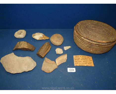 An antique woven reed lidded basket containing a collection of; fossils, petrified wood, ancient pottery, stone tool fragment