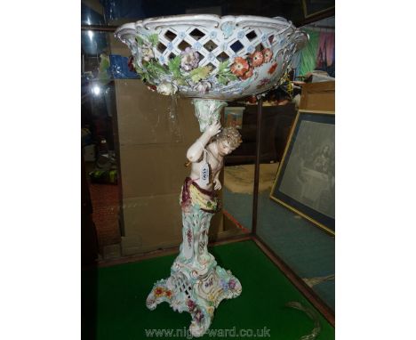 A very large ceramic table centrepiece, the stand in the form of a male nymph holding the floral encrusted and lattice work b