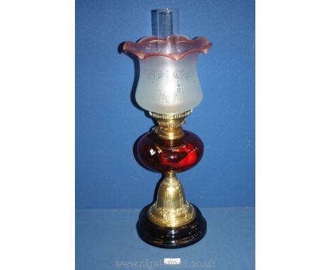 A Nouveau style brass Oil lamp with cranberry glass reservoir and fluted etched shade, 23'' tall overall with chimney