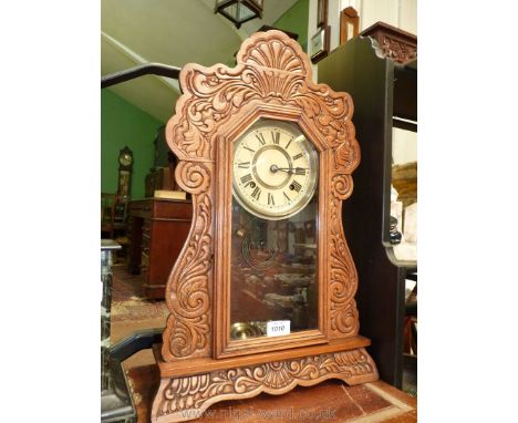 A mantle clock carved surround having floral motif and scrolling, complete with key and pendulum, 22'' tall.