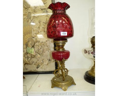 An oil Lamp with an ornate brass base, red glass ribbed reservoir, double wick burner, cranberry fluted shade and clear chimn