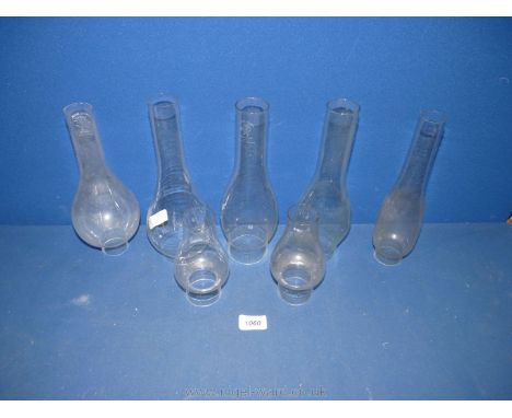 Seven assorted oil lamp chimneys, various sizes.