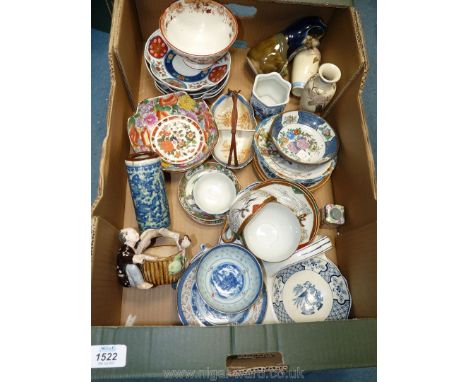 A quantity of oriental style china including cups and saucers, small basket, man with a bird perched on a basket, blue and wh