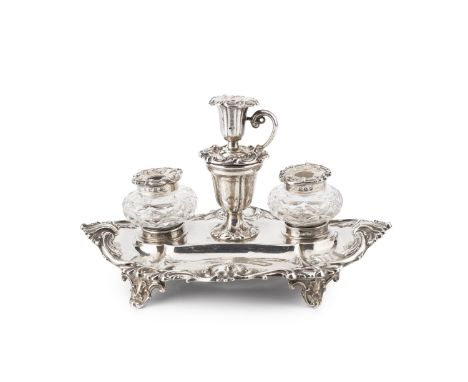 A mid Victorian silver inkstand, of shaped oval form with foliate scroll borders, fitted a pair of silver mounted inkwells fl