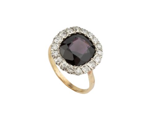 A diamond set cluster ring, centred with a cushion-shaped stone of purplish-red hue, bordered by circular vari-cut diamonds, 
