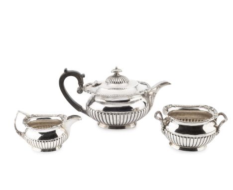 An Edwardian Scottish silver three piece bachelor's tea service, with gadrooned and foliate scroll borders and part-lobed bod
