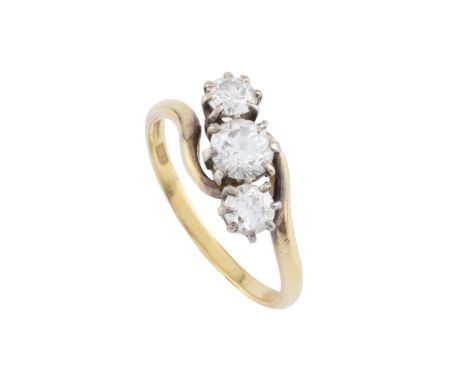 A diamond three stone ring, of crossover design, obliquely claw set with graduated round brilliant-cut diamonds, two colour p