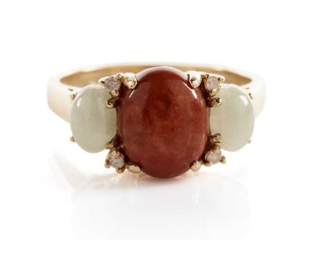 A jadeite and diamond dress ring, the central red jadeite cabochon flanked by green jadeite cabochons, interspaced with round