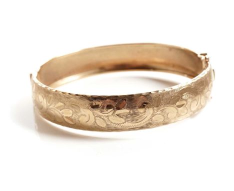 A 9ct yellow gold bangle, with engraved scrolling foliate decoration, 66mm wide, 14.6g gross.