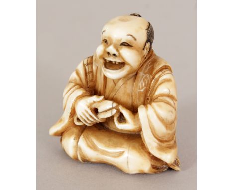 A SIGNED JAPANESE MEIJI PERIOD STAINED IVORY NETSUKE OF A KNEELING JOVIAL MAN, holding a pair of clippers, the base with an e