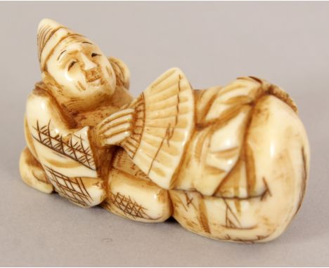 A SIGNED JAPANESE MEIJI PERIOD IVORY NETSUKE OF EBISU KNEELING BEFORE A BAG, and holding a fan, the base with an engraved sig