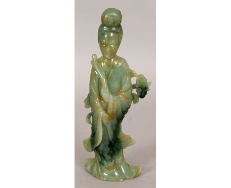 A CHINESE JADE FIGURE OF GUANYIN, standing in flowing robes before lingzhi, the predominantly green stone with darker spinach