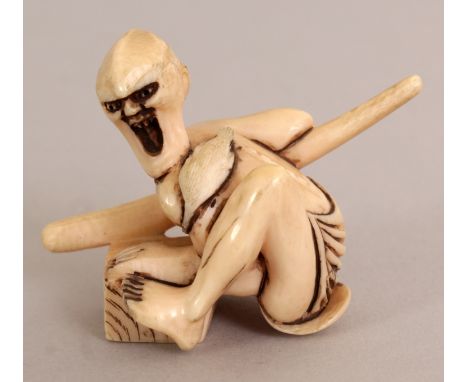 AN EARLY 20TH CENTURY SIGNED JAPANESE IVORY NETSUKE OF A STYLISED ONI, squatting and bearing a sword, the base with a red sta