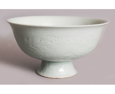 A LARGE CHINESE CELADON STEM BOWL, moulded beneath the glaze with two dragons pursuing flaming pearls, the interior centred w