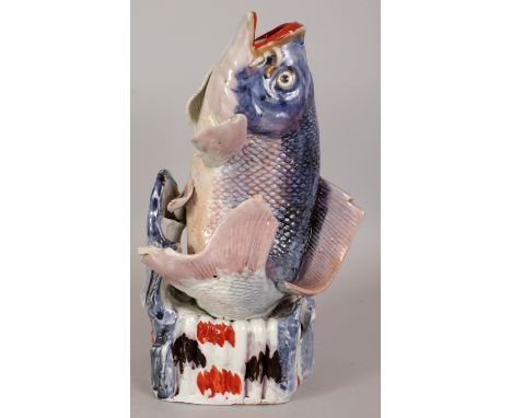AN 18TH CENTURY JAPANESE EDO PERIOD PORCELAIN MODEL OF A KOI CARP, leaping from a stylised wave base, applied with a variety 