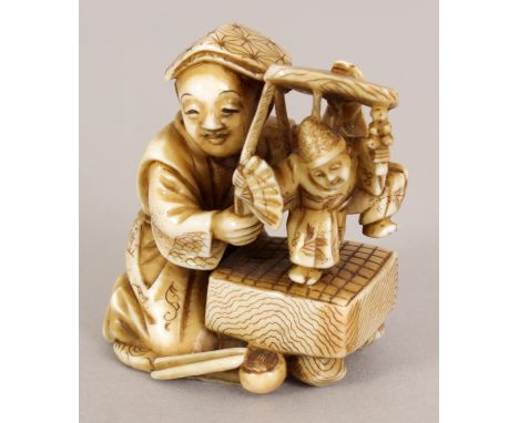 A GOOD QUALITY SIGNED JAPANESE MEIJI PERIOD STAINED IVORY OKIMONO OF A PUPPETEER, kneeling and holding his puppet before him,